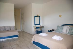 a hotel room with two beds and a mirror at Castri Village Hotel in Palekastron