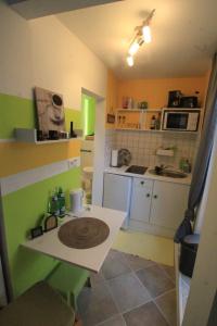 uma pequena cozinha com armários verdes e brancos e uma mesa em Maison No.9 em Rosbach vor der Höhe