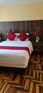 a bedroom with a large bed with red pillows at Apart Hotel Incamin in Arequipa