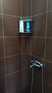 a brown tiled bathroom with a shower with two products on a shelf at Apartmani Draškovic - Goč in Biserske Kuće