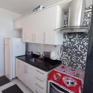 une cuisine avec des armoires blanches et un comptoir noir dans l'établissement Condominio Recanto das palmeiras, à Campos dos Goytacazes