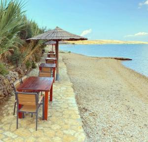 una fila di tavoli e sedie con ombrellone in spiaggia di Luxury Mobile Home Marbella 167 -Terra Park SpiritoS a Kolan