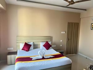 a bedroom with a large bed with red and white pillows at Hotel Gaurav Residency in Pune