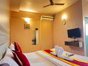 Hotel Gaurav Residency في بيون: غرفة فندقية بسرير وتلفزيون بشاشة مسطحة