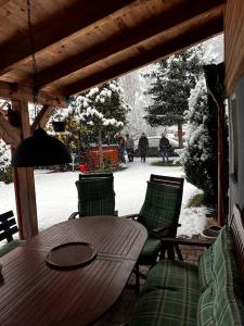 una mesa de madera y sillas en un porche en la nieve en Party/Wellness House Pool/Hot tub/Sauna en Pelhřimov