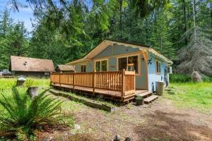 a small house with a porch and a deck at Cozy Cedar Cabin Steps Away From Mt. Rainier in Ashford