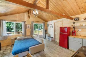 Cozy Cedar Cabin Steps Away From Mt. Rainier في أشفورد: غرفة نوم بسرير وثلاجة حمراء