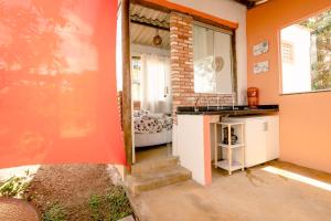 a small kitchen with an orange wall and a window at Chalé charmoso e aconchegante, pertinho da cidade. in Brasilia