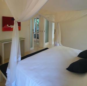 une chambre avec un lit blanc avec une fenêtre dans l'établissement Trancoso Terravista Villa Floresta, à Trancoso