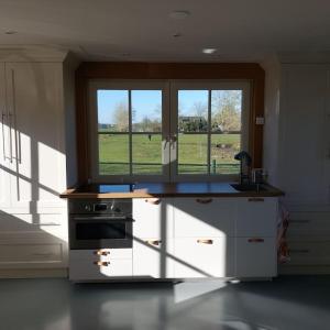 een keuken met een fornuis en een raam met een veld bij Tiny house Wakker in Eemnes
