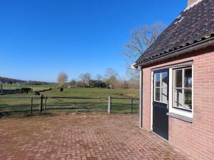 a brick house with a fence and a field at Tiny house Wakker in Eemnes