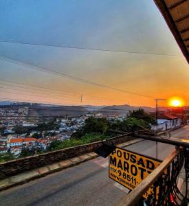 un cartel en un balcón con la puesta de sol en el fondo en Pousada Marotta, en Ouro Preto