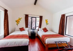 two beds in a room with two windows at Hotel Kuska Home in Cusco