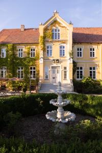 una fontana bianca di fronte a una grande casa di Gutshauszimmer Premium a Neu Gaarz
