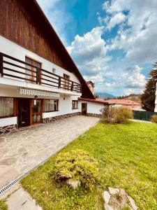 a house with a grassy yard next to a building at Cheerful 4-bedroom & kids friendly home in Predeal