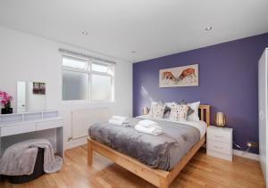 a bedroom with a large bed with purple walls at Lovely 4 Bedroom London Home with Free Parking, Garden, WiFi By Roost Accommodation in Kingston upon Thames