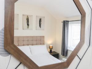 a mirror reflecting a bedroom with a bed and a window at The Crescent Escape in Colwyn Bay