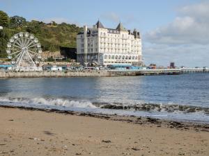a beach with a hotel and a ferris wheel at The Crescent Escape in Colwyn Bay