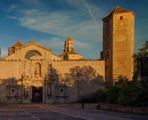 ein Gebäude mit einem Uhrturm und einer Kirche in der Unterkunft Cal Passió in Vimbodí