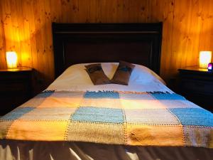 a bed with a colorful quilt and two lamps on tables at Campito Refugio in San José de Maipo