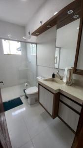 een badkamer met een wastafel, een toilet en een spiegel bij Pousada Miguel Penha Sc in Penha