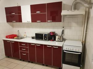 een kleine keuken met rode kasten en een magnetron bij Central Apartment Bucharest Mall in Vitan