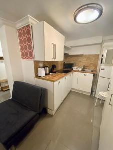 una pequeña cocina con armarios blancos y una silla negra en Lower ground Bell street, en Londres