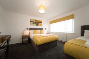 a bedroom with two beds and a desk and a window at Belmont Budget Apartment in Stockton-on-Tees