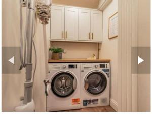 una lavadora y secadora en una cocina con armarios blancos en St Marg’s Hideaway; Grade II listed luxury apartment in the heart of Cheltenham - gateway to the Cotswolds! Sleeps 4 - outdoor seating and free private parking!, en Cheltenham