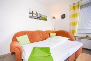 una sedia arancione con un letto in una stanza di Hanseat I Whg 45 a Grömitz