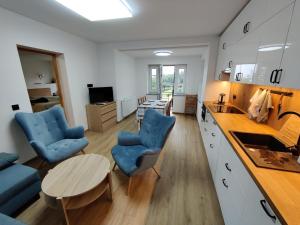a kitchen and living room with blue chairs and a table at Apartament De Lux LIDIA in Karpacz