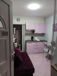 a kitchen with pink cabinets and a table and chairs at Studio apartman"Mirjana", Podhum 368 in Podhum