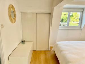 ein weißes Schlafzimmer mit einem Bett und einem Fenster in der Unterkunft Charmante petite maison flamande in Bondues