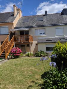 ein Haus mit einer Terrasse und einem Garten mit Blumen in der Unterkunft Appartement 60 m2 indépendant au 1er étage d'une maison de ville in Lanester