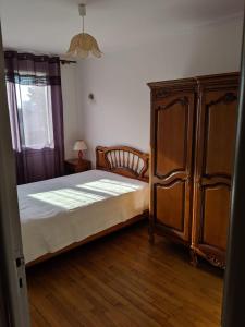 Schlafzimmer mit einem Bett und einem Holzschrank in der Unterkunft Appartement 60 m2 indépendant au 1er étage d'une maison de ville in Lanester