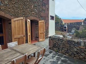 un patio con una mesa de madera y una pared de piedra en Casa de los Arcos, en Mocanal