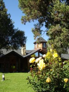 una casa con cenador y algunas rosas amarillas en UNIQUE ARELAUQUEN SUITE en San Carlos de Bariloche
