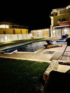 una piscina por la noche con sillas azules junto a un edificio en Villa Sky en Hurghada