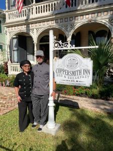 a man and woman standing next to a pole in front of a building at Coppersmith Inn Bed And Breakfast in Galveston