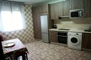 een keuken met een tafel, een fornuis en een vaatwasser bij HABITACION DE DOS CAMAs BEC in Barakaldo