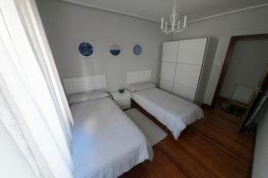 a bedroom with two beds and a chandelier at Apartamento centro Barakaldo BEC, Parking Incluido in Barakaldo
