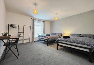 Stott House - Bright Spacious Townhouse 15 Minutes to Central Manchester With Free Parking في مانشستر: غرفة نوم بسرير وكرسي وطاولة