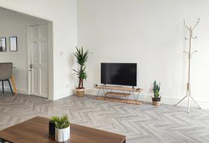 a living room with a flat screen tv on a white wall at Stott House - Bright Spacious Townhouse 15 Minutes to Central Manchester With Free Parking in Manchester