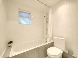 a white bathroom with a toilet and a bath tub at Stott House - Bright Spacious Townhouse 15 Minutes to Central Manchester With Free Parking in Manchester