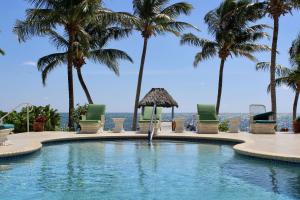 una piscina con palmeras y sillas en Tara Del Sol Resort, en San Pedro