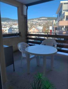 a white table and two chairs on a balcony at Magnifique T3 avec balcon vue montagne , plein centre et proche du lac in Gérardmer