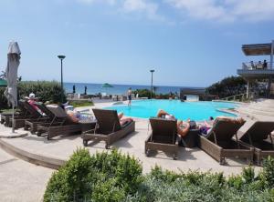 a group of people laying in chairs by a swimming pool at Zimbali 20 Phezulu Villa in Ballito