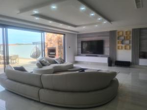 a living room with a white couch and a tv at Zimbali 20 Phezulu Villa in Ballito