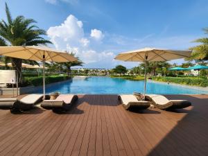 a group of chairs and umbrellas next to a pool at Florence Villa - Novaworld Phan Thiet in Phan Thiet