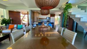 uma sala de jantar com uma grande mesa de madeira e cadeiras em Kalug - Duplex PÉ NA AREIA com 4 suítes, piscina e churrasqueira privativa na Praia do Sul! Perfeito para família - Wifi 300mb! em Ilhéus